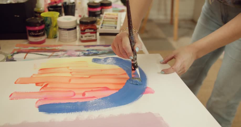 Woman painting with brush on canvas inside studio