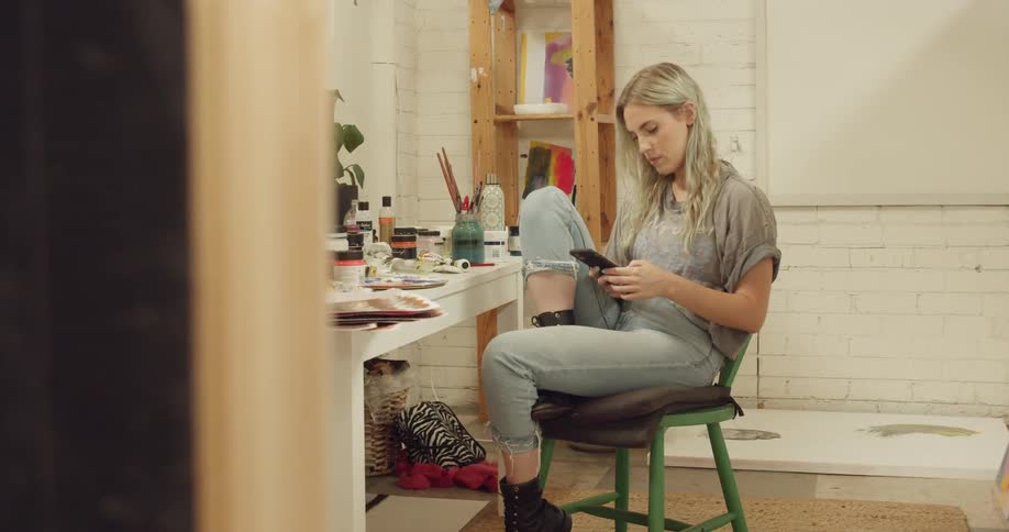 Woman sits at table scrolling through mobile phone