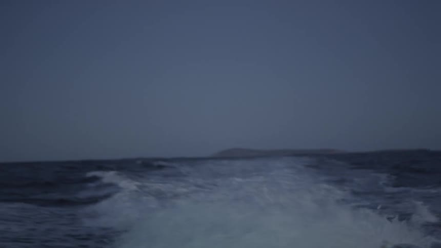 Looking back from onboard a fast boat leaving a wide and foaming wake in the distance