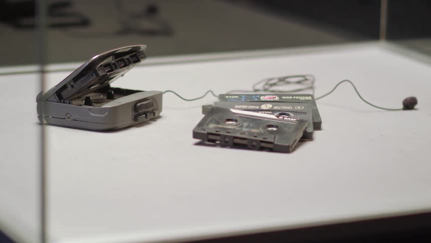A tape player and cassettes sitting on a table with earbuds