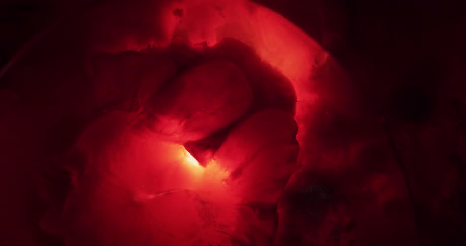 A red globe explodes in a dark fluid
