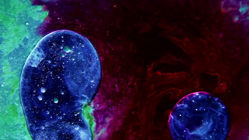 In the midst of a red and green fluid two blue droplets are suspended and moving around