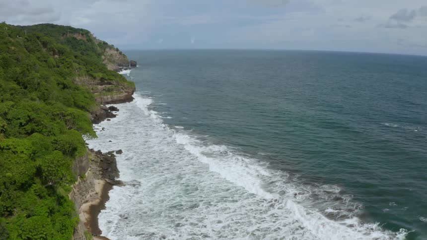 Waves crash below the cliffs along a coastline