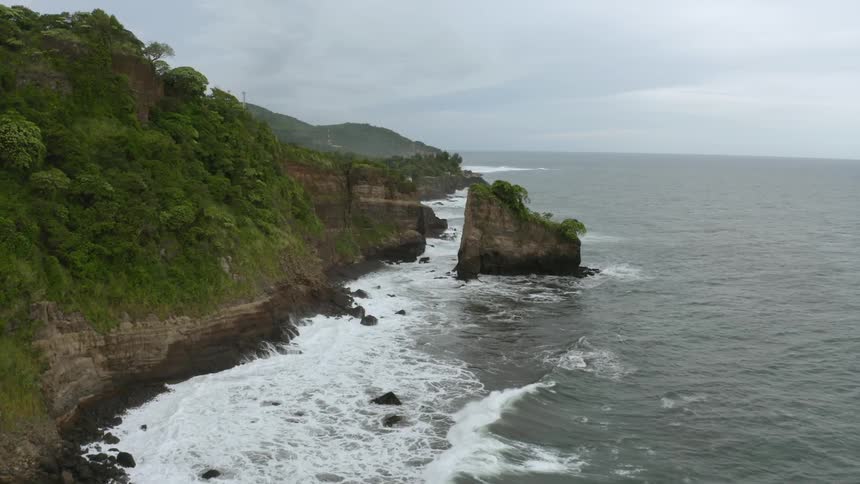 Waves crash on the shore below cliffs