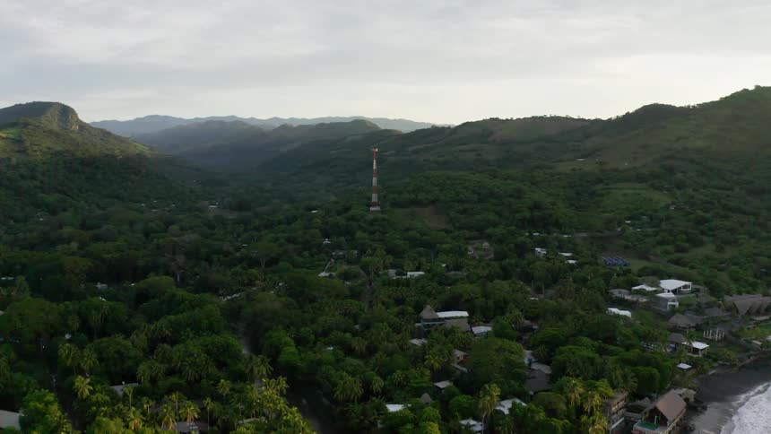 A red and white tower stands in the center of a village in a forested area
