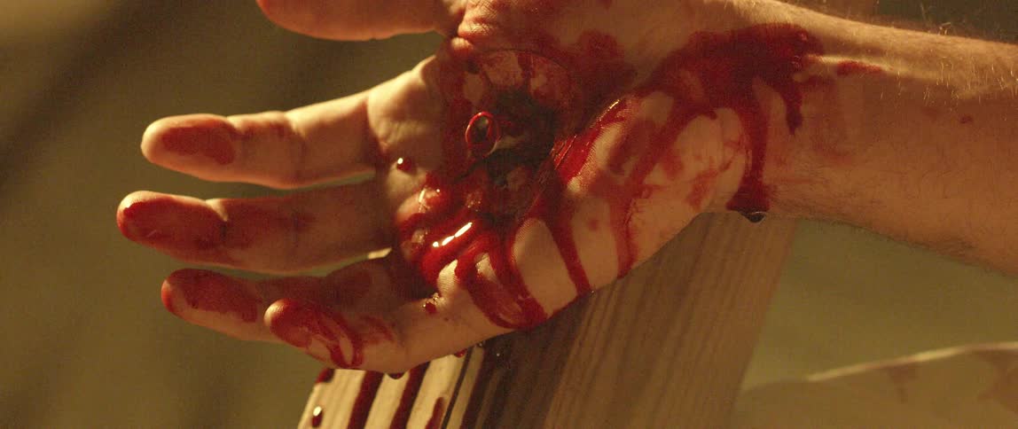 A blood covered hand nailed to a piece of wood