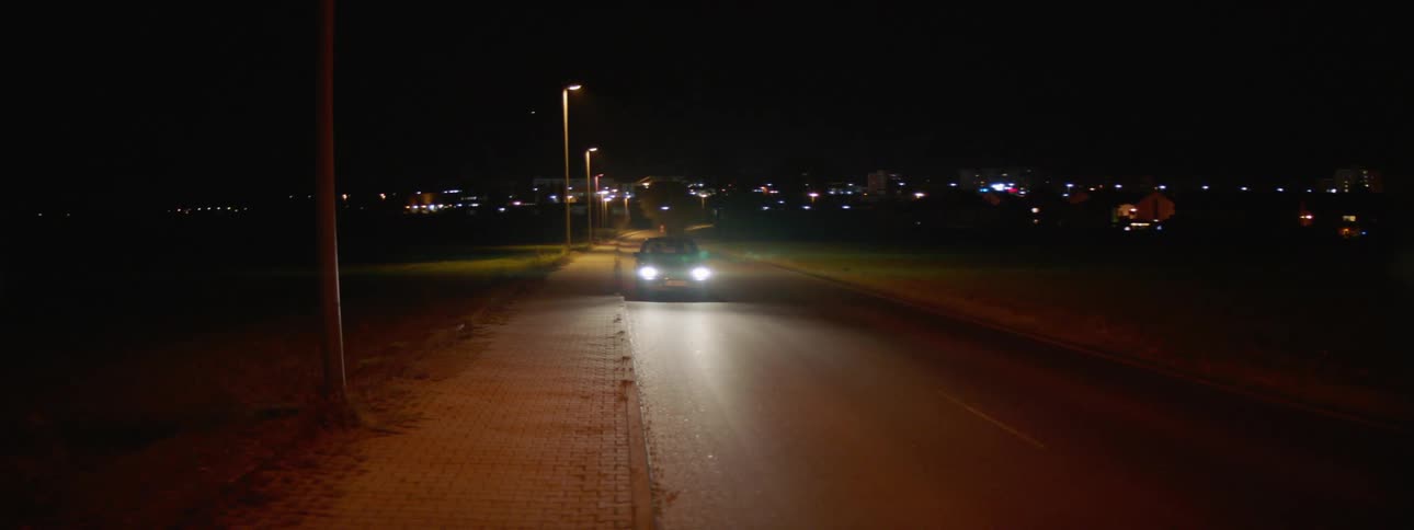 A car drives down a street at night