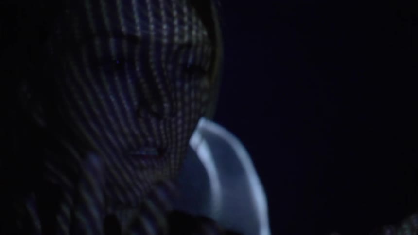 A young woman looks at her hands as strobing lights reflect on them