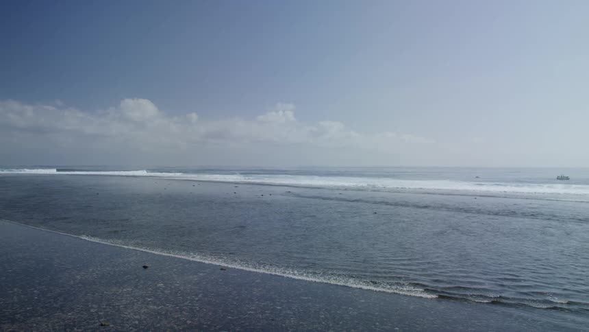 A beach with waves with the sky in the background