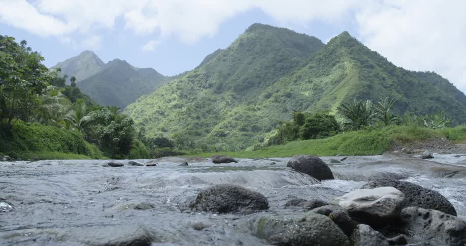 Water rushes through a creek with hills behind it