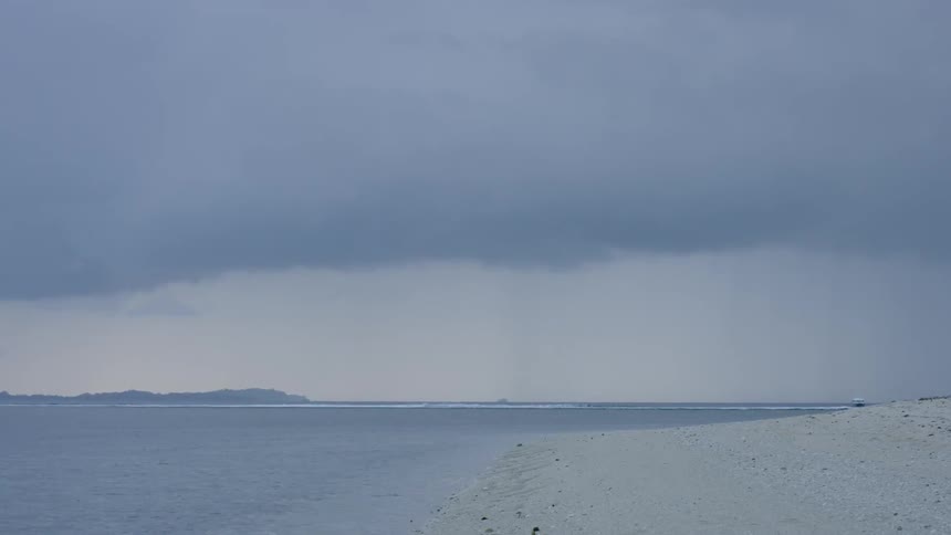 Rain clouds float above a sandy beach