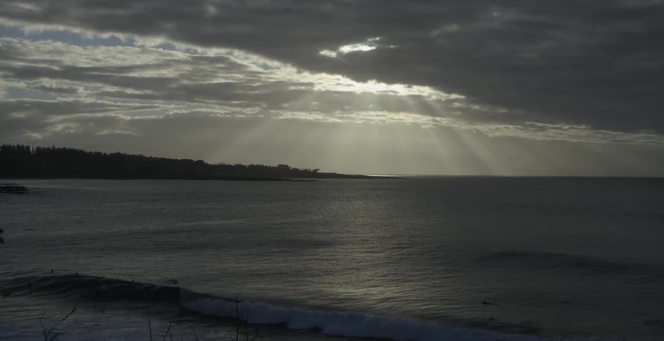 The sun peaks in through the clouds over the water