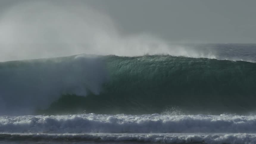 People swim through a large wave in the ocean