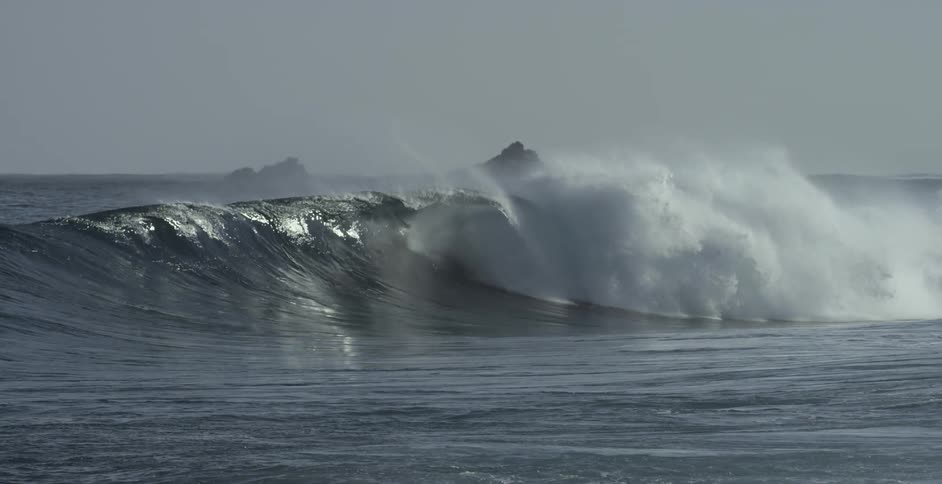 A large ocean wave is crashing toward the shoreline