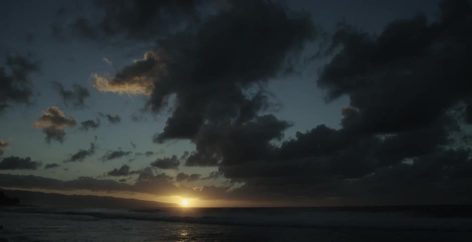 Sun setting in a wide open landscape with dark clouds