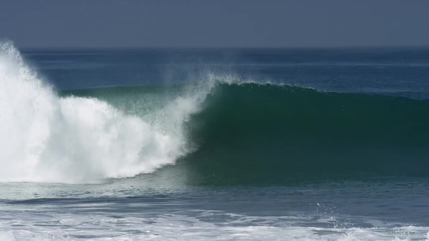 A large wave rolls down the shore
