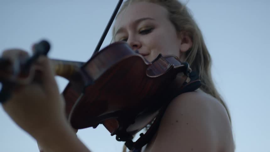 A woman putting a violin on her shoulders and playing it