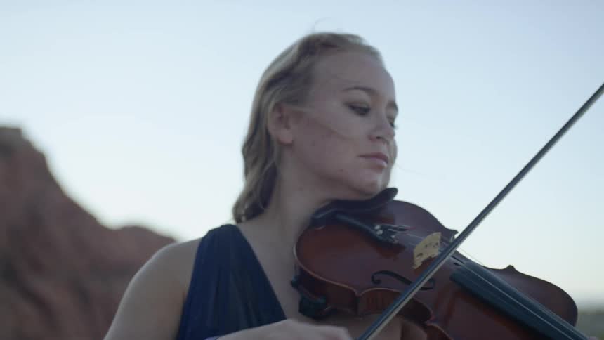 A woman in a blue dress is playing the violin