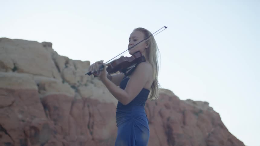 A young woman plays a violin outside