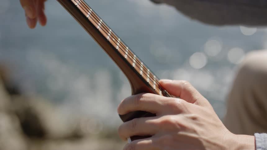 A man plays the strings of his guitar