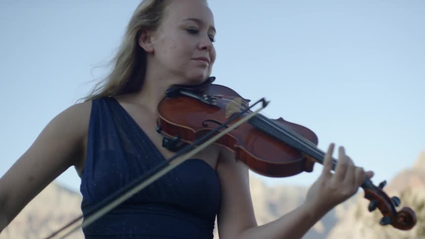 A woman plays the violin in a remote mountain area