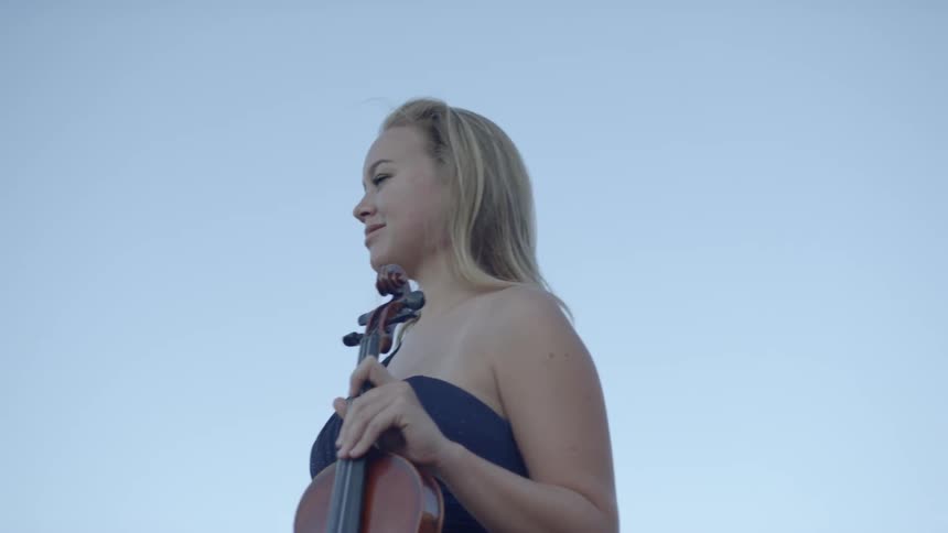 A woman smiles holding a violin