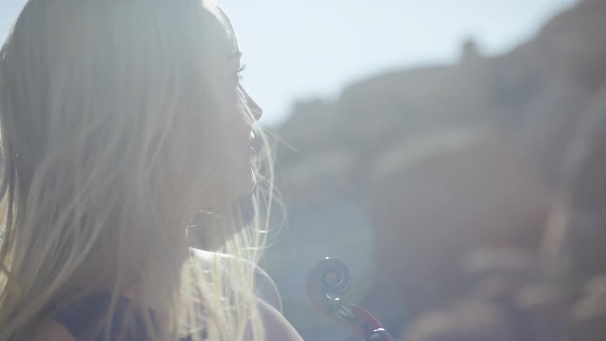 A woman is holding her violin outside
