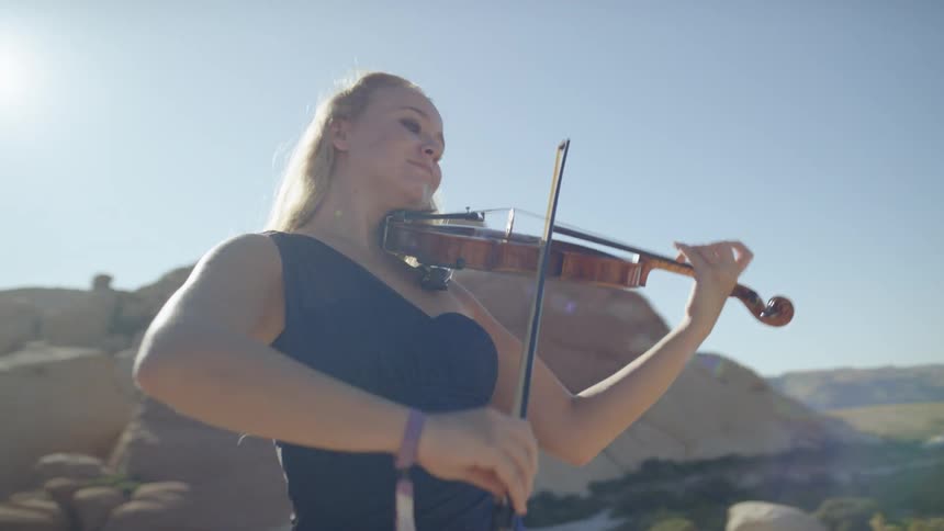 A young woman plays the violin outside