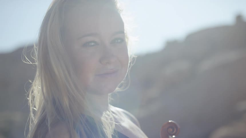 A woman holds her violin on a sunny day