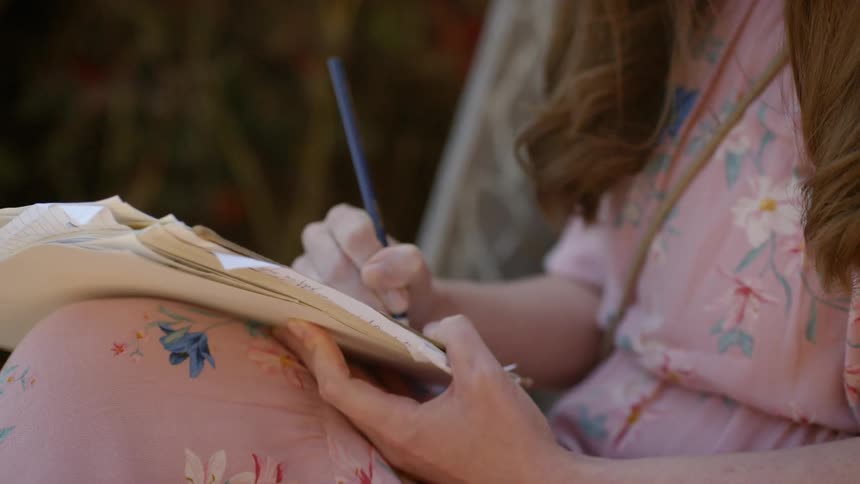 Ayoung girl sits and writes in a book