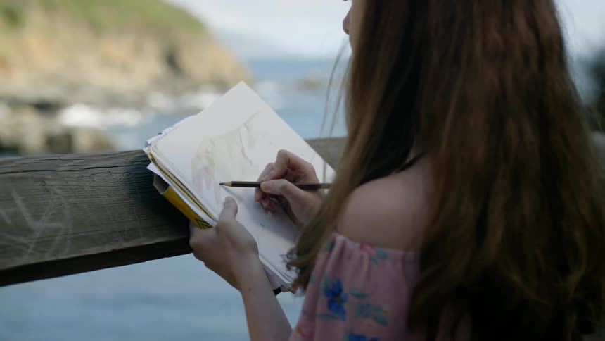 A woman is sketching by the shore