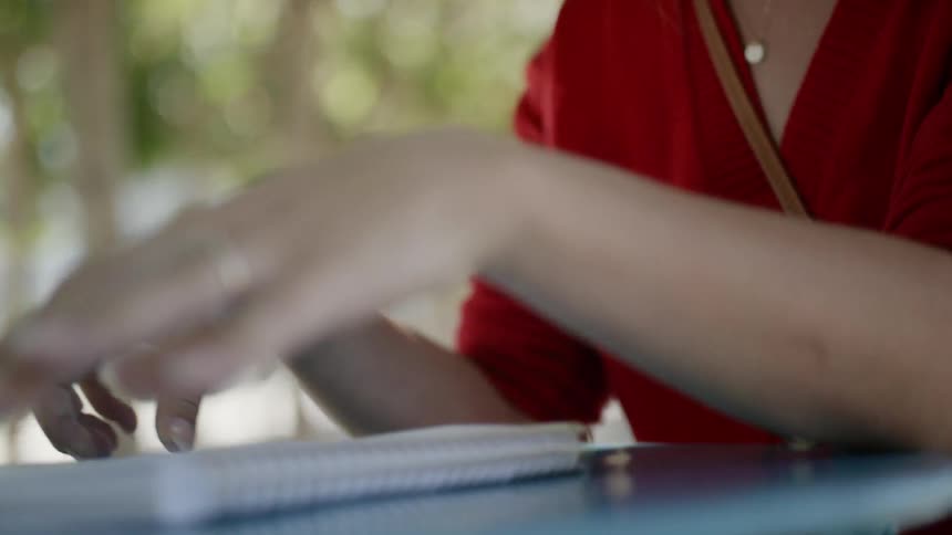 A woman smiles while opening her notebook