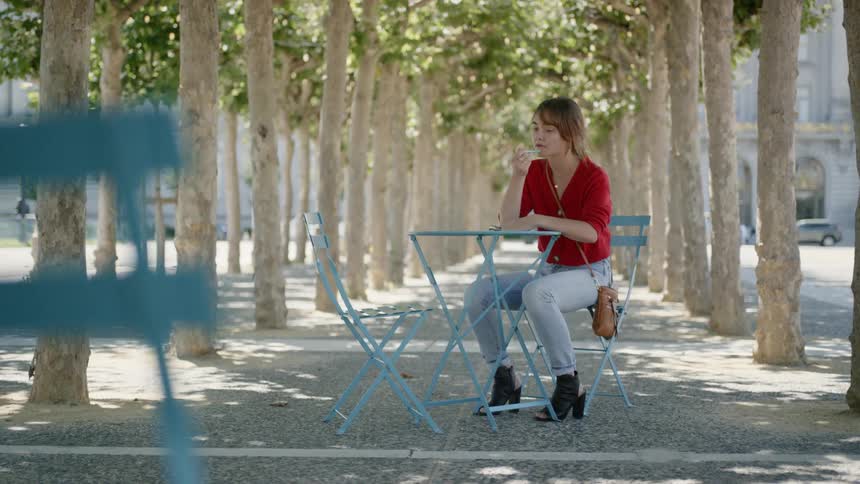 Woman sitting at the blue table thinks about something to write down on the tree road