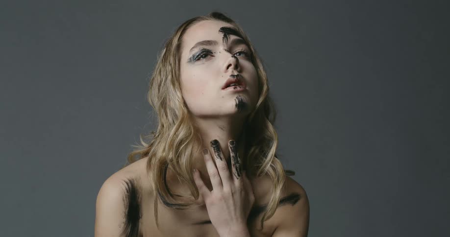 A woman has black paint on her face and hands