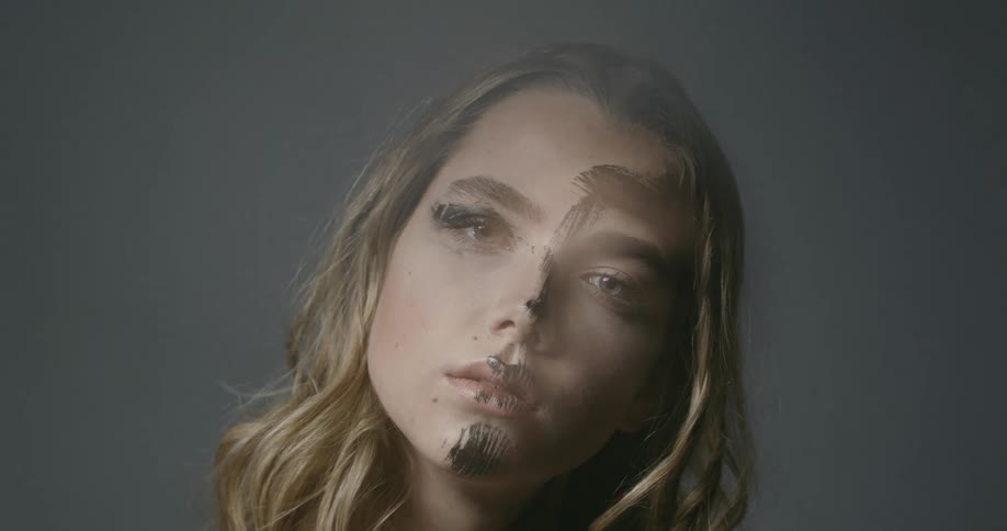 Close up of female model with black paint on face moving head to right in a studio