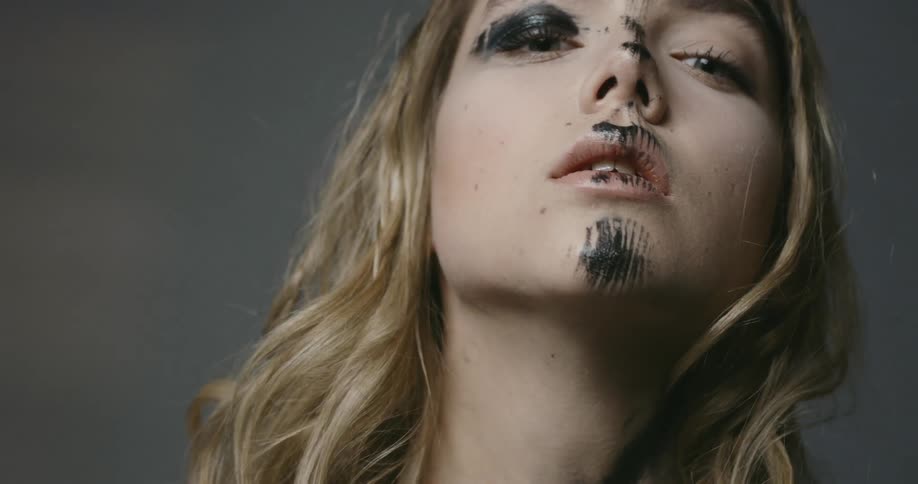 A young caucasian woman with streaks of black paint on her face