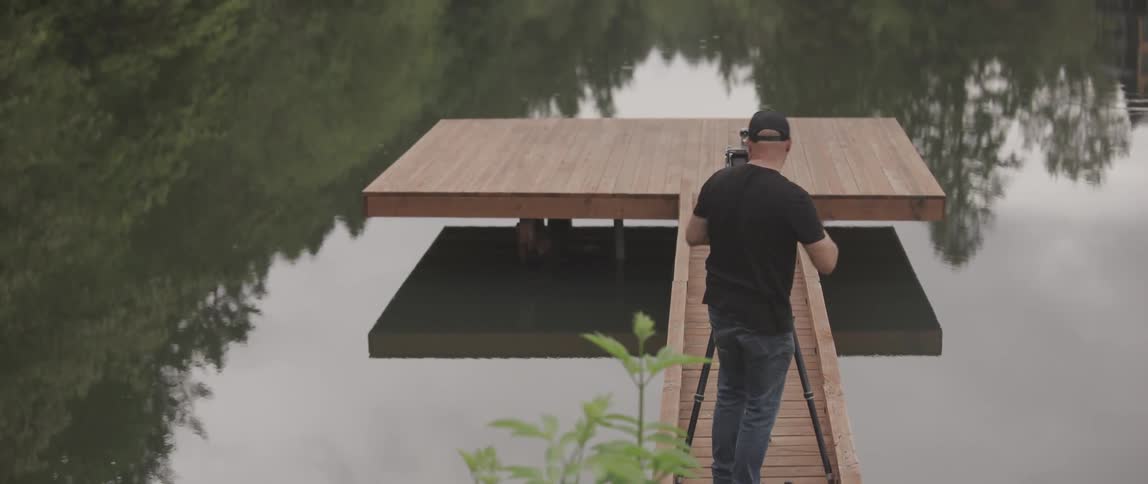A man stands on a dock and takes photos