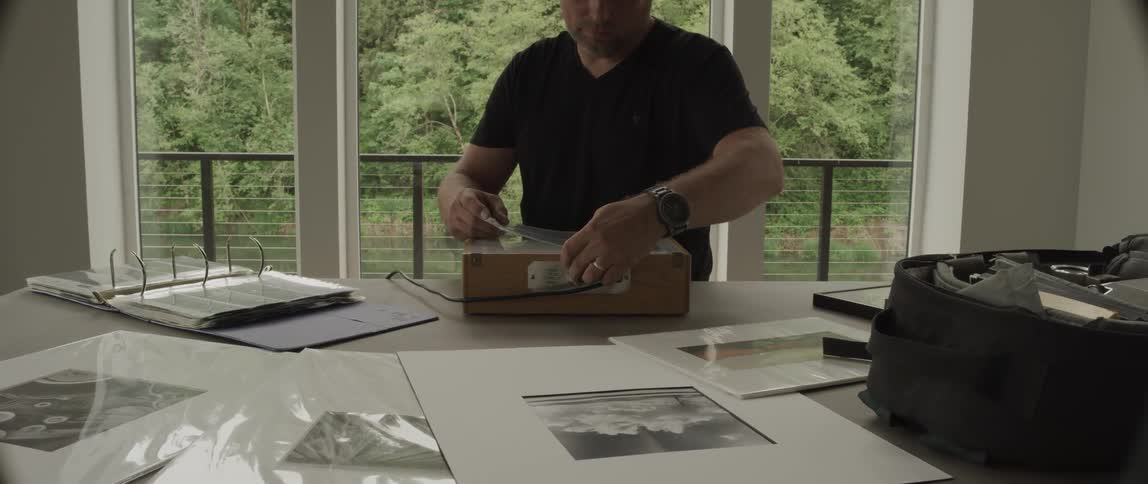 A man looking at photos on a light box in a room