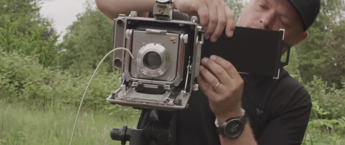 A man is setting up a camera outdoors