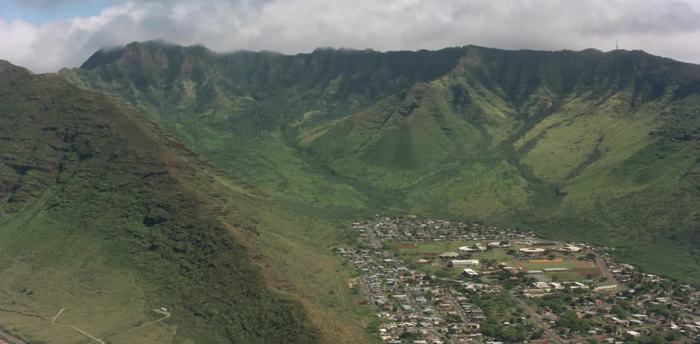 An aerial view of grassland mountains is displayed by a neighborhood