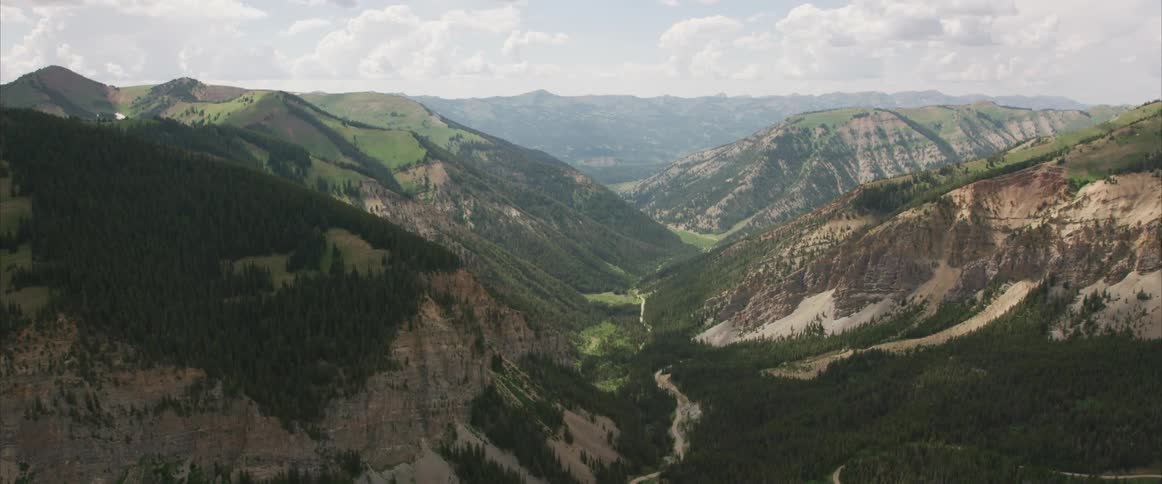 Forest covered mountains and valleys under cloudy sky during the day