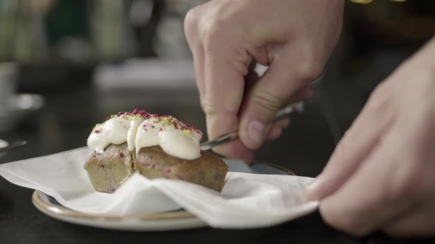 Someone cutting apart a small frosted cake