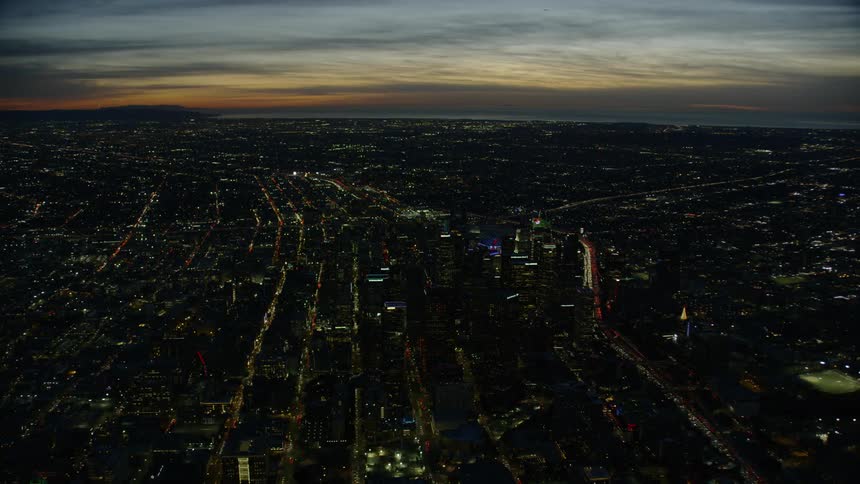 An aerial view of a large city by the ocean at dusk