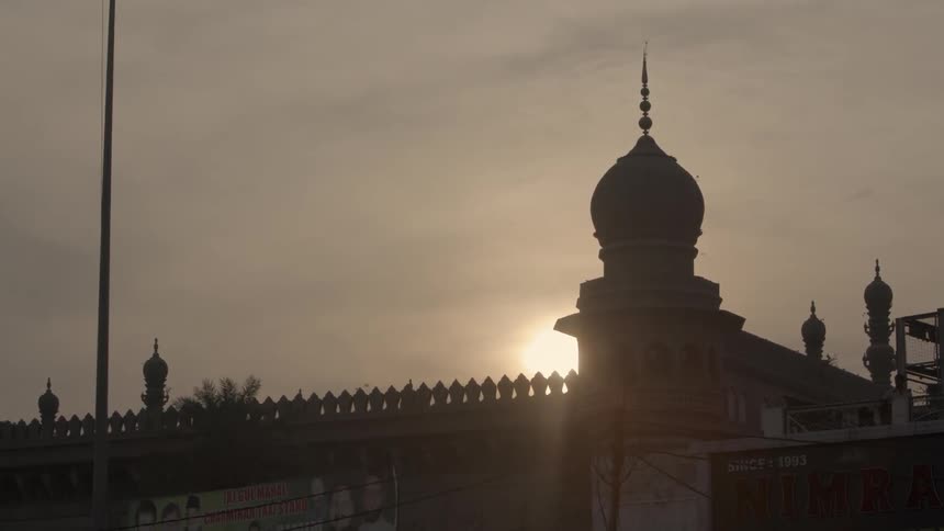 The sun sets behind a mosque