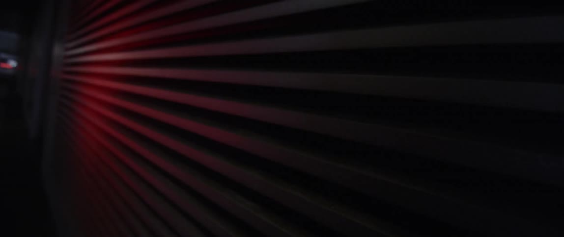 Inside of a darkened garage a red light shines on a metal rollup garage door