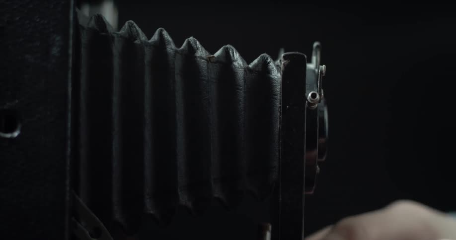 A photographer adjusts the accordion lens of a vintage camera