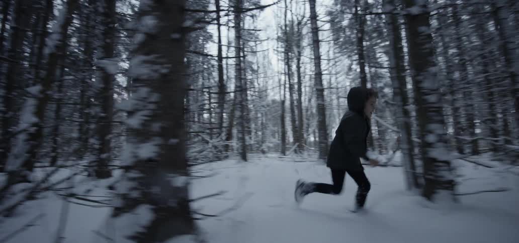 A child running through a snowy woodland