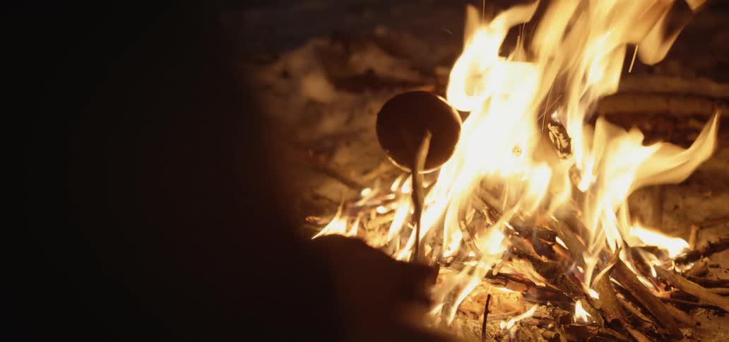 A person roasts a marshmallow over a fire