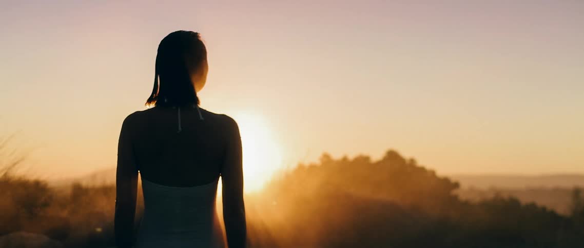 A woman in a white bathing suit looking into the sunset