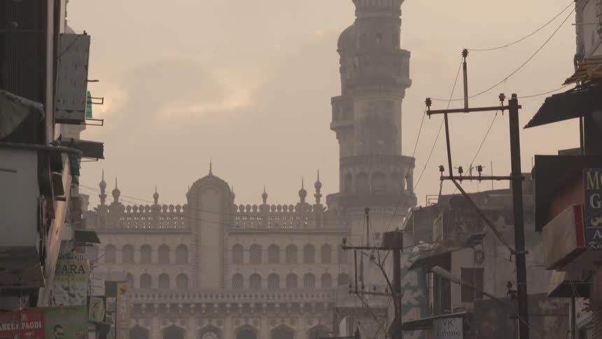 People walk down a street in a very smoggy foreign city